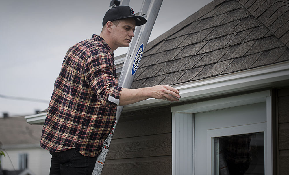 Person on a ladder inspecting their gutters